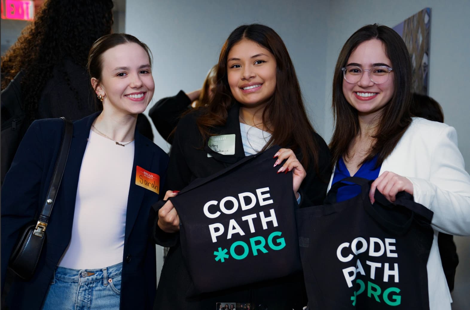CodePath students holding CodePath tote bags